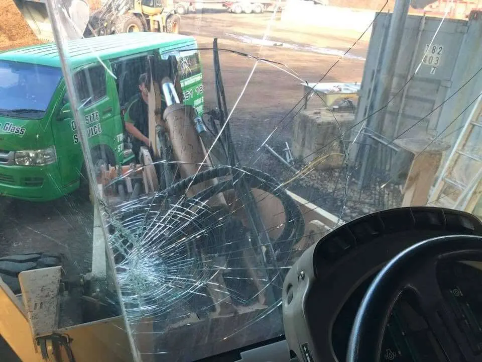 Cracked machinery windscreen seen from inside the cab with the service van outside