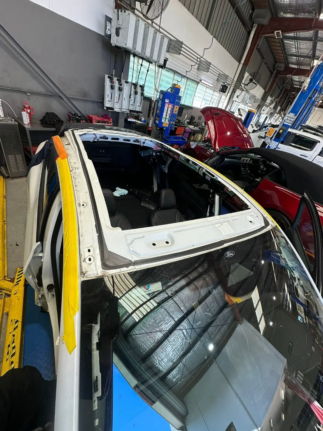 Full-length panoramic roof glass being fitted to a car in the workshop