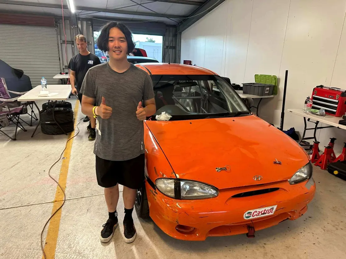 Customer giving a thumbs up beside a race car after windscreen work