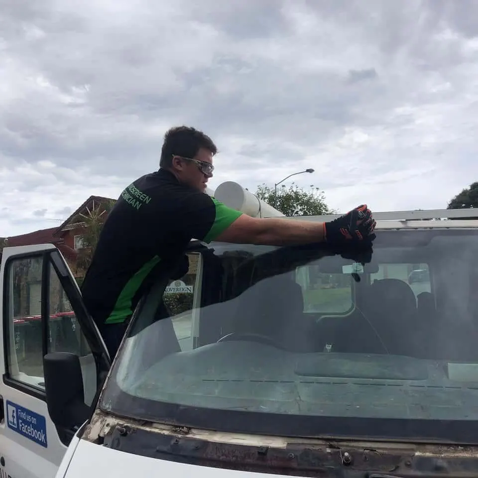 Fitter lifting a windscreen out of a light truck at the customer’s address