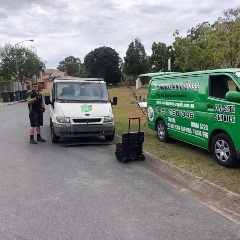 Express Auto Glass fitter and van beside a vehicle on a suburban street