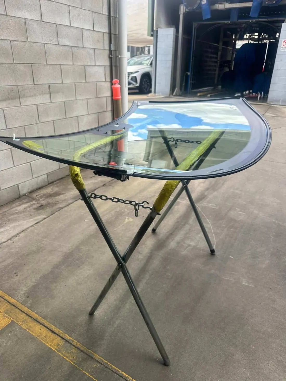 New windscreen primed on a glass stand outside the workshop